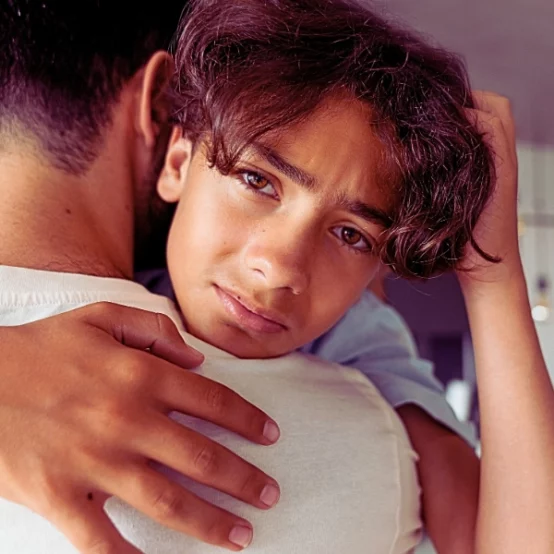 Troubled young man giving a tight hug by his dad.