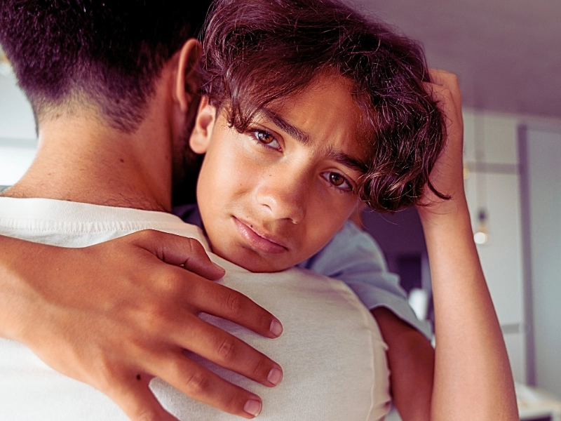 What Is Temporary Protected Status, and How Does it Affect Immigrants in the US? 1 Troubled young man giving a tight hug by his dad.