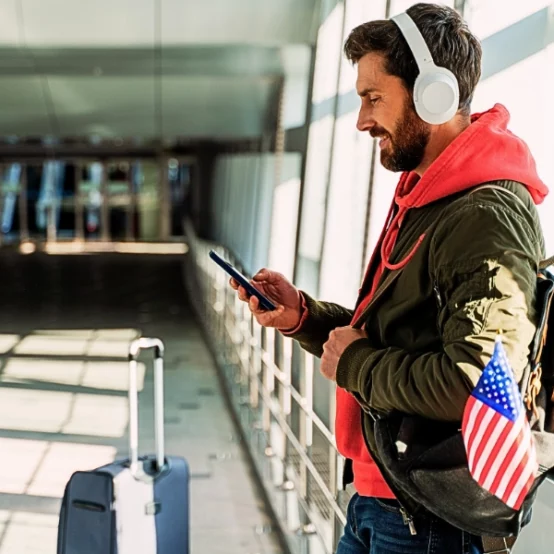 Close up view of the traveler man wearing headphones looking at his smartphone. travel while an immigration case is pending