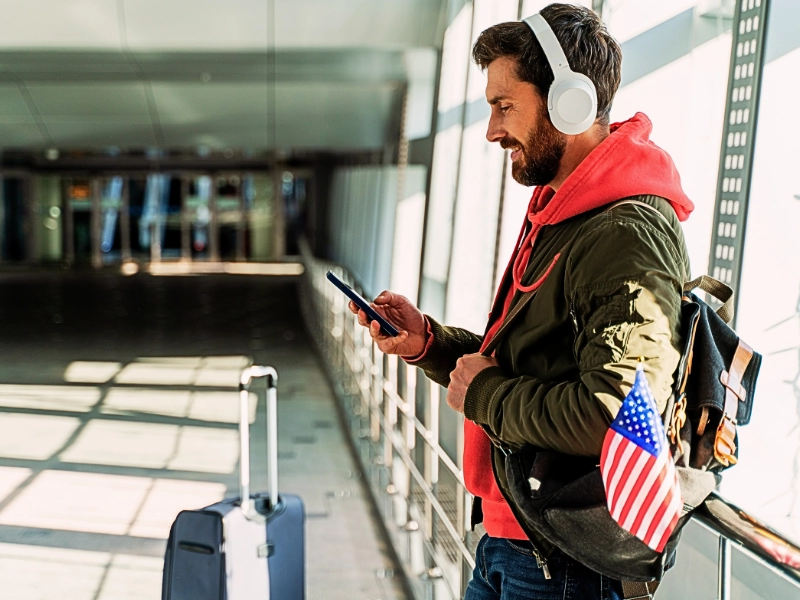 Can You Travel While an Immigration Case Is Pending in Chicago? 1 Close up view of the traveler man wearing headphones looking at his smartphone. travel while an immigration case is pending
