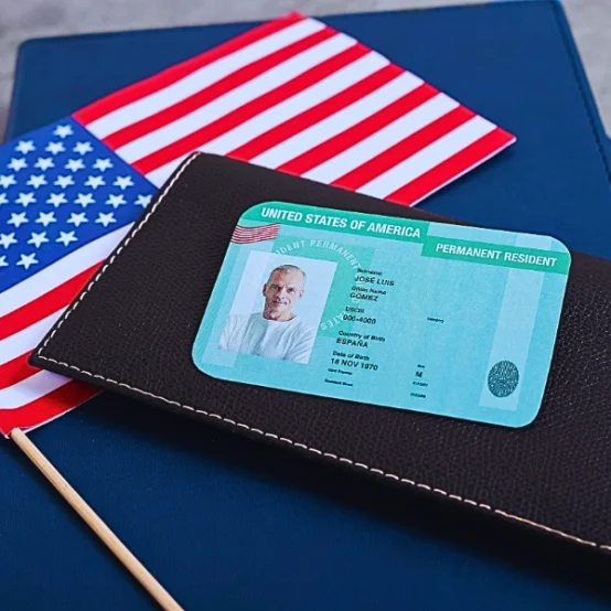 Top view of green card on a black wallet and American flag. Get a Green Card Through Marriage If You Overstayed a Visa